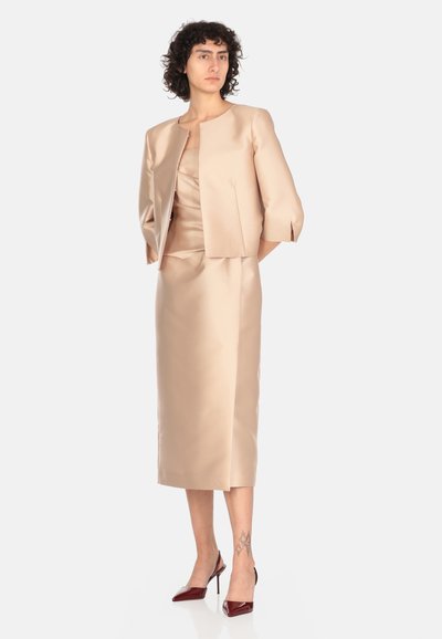 Set di vestito in satin beige con corpetto aderente, gonna al ginocchio e giacca cropped coordinata con maniche tre quarti e spacchi laterali.