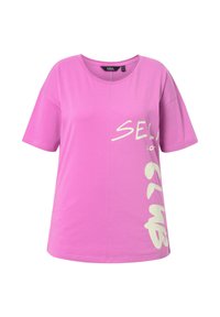 Camiseta rosa de gran tamaño hecha de una tela suave. Presenta mangas cortas y un audaz texto gráfico blanco en la parte frontal. Cuello redondo y corte relajado.