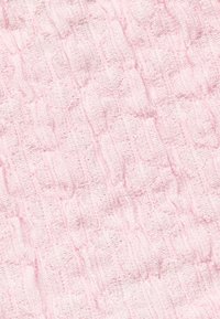Struktureret stof i blød pink med et ribbet mønster med varierende højder, der skaber taktil interesse og visuel dybde.
