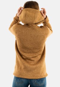 Sudadera con capucha de un cálido color marrón, que presenta una tela texturizada. La parte trasera muestra un ajuste relajado con un dobladillo ligeramente curvado.