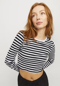 Svart og hvit stripete langermet crop top med rund hals, laget av ribbestrikket stoff, med en tettsittende design og rynkete ermer.
