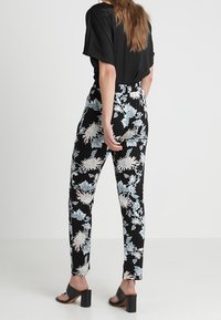 Kalhoty s květinovým vzorem v černé barvě se světle modrými a bílými akcenty; slim-fit střih s vysokým pasem a délka do kotníků; hladká látka.
