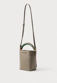 Torebka typu bucket w szarej skórze z zielonym, spiralnym uchwytem. Wyposażona w złote akcesoria i regulowany pasek. Prosty, strukturalny design.