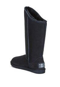 Černé semišové boty s vysokým designem, hladkým povrchem a podšívkou z umělé kožešiny. Mají kontrastní švy a kovovou značku na boku.