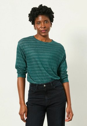 Tee mit teal gestreiftem Langarmdesign und Rundhalsausschnitt, kombiniert mit dunkelblauen hochtaillierten Jeans. Das Hemd hat eine lockere Passform und eine dezente Textur.