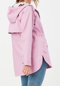 Jasnoróżowa, wodoodporna kurtka z kapturem, elastycznym pasem, zatrzaskami i bocznymi kieszeniami. Posiada kwiatową podszewkę widoczną przy szyi.