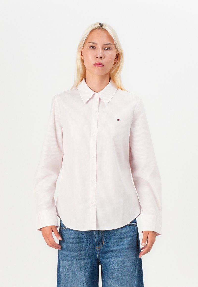 Camicia button-up rosa chiaro con colletto, maniche lunghe e sottili righe verticali; presenta un piccolo logo del marchio sul petto.