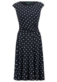 Robe marine avec des pois blancs, manches courtes, corsage ajusté avec un détail torsadé et une jupe évasée qui arrive aux genoux.