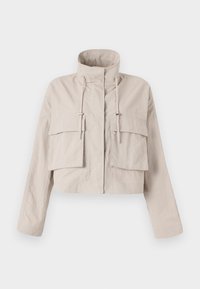 Veste beige raccourcie en tissu léger, dotée d'un col montant, d'un cordon de serrage ajustable et de deux grandes poches à rabat à l'avant.