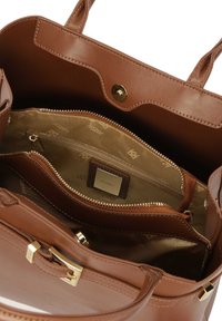 Barna bőr bevásárlótáska aranyszínű fém kiegészítőkkel, cipzáras belső zsebbel és mintás textil béléssel, amely tágas belső kialakítást mutat.