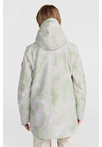 Light-colored jacket with a camouflage pattern in pale green tones. Features a hood, long sleeves, and a relaxed fit. Branding on the back.