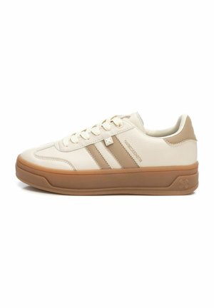 Zapatillas beige con tres franjas marrones, suela de goma, parte superior de cuero vegano texturizado y cierre de cordones. Logo sutil en el lateral.