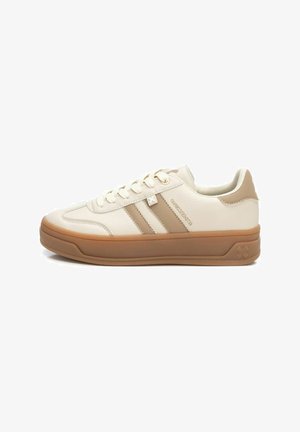 Zapatillas beige con tres franjas marrones, suela de goma, parte superior de cuero vegano texturizado y cierre de cordones. Logo sutil en el lateral.