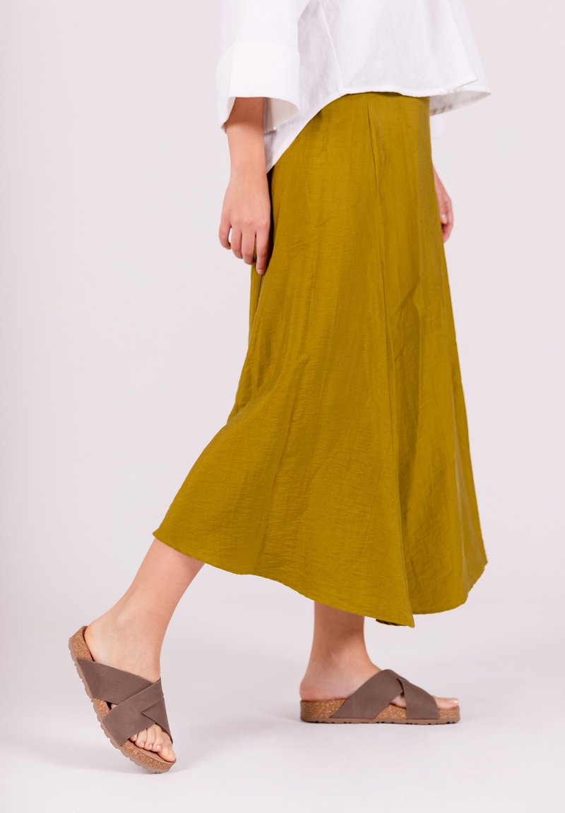 Jupe midi vert olive en tissu texturé, associe avec des sandales marron à brides croisées dotées d'un sol en liège. Design simple et décontracté.