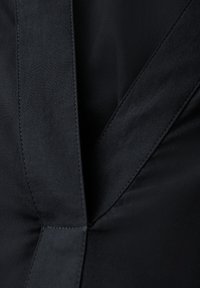 Tessuto nero con una superficie liscia, caratterizzato da un design strutturato e cuciture visibili. Include pannelli angolari e una finitura pulita.