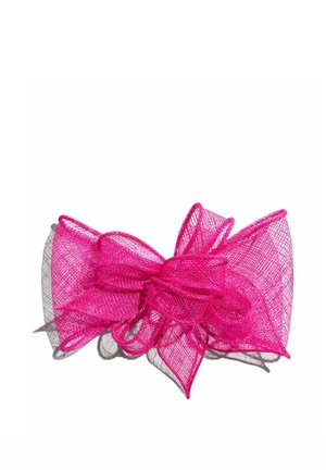 Noeud en tissu résille rose vif avec plusieurs boucles et texture en couches projetant une ombre sur un fond blanc.