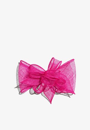 Kirkkaan pinkki verkkokangasrusetti, jossa on useita silmukoita ja kerroksellinen rakenne, joka heittää varjon valkoista taustaa vasten.