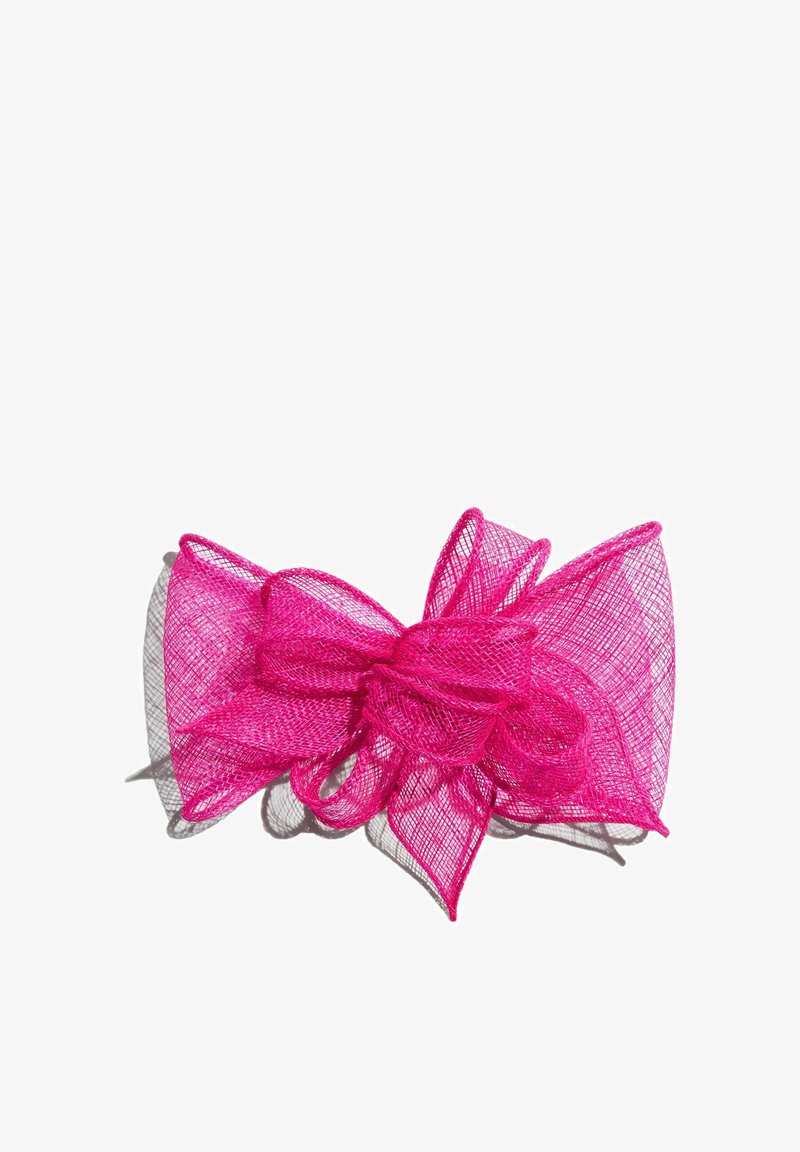 Fundă din plasă de material roz aprins, cu mai multe bucle și textură stratificată, proiectând o umbră pe un fundal alb.