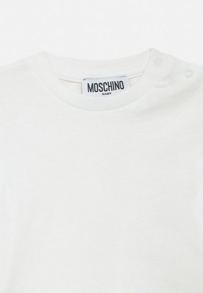 White baby t-shirt with round neck, snap buttons on shoulder, and "Moschino Baby" label inside collar.