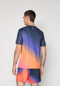 Kortærmet sports shirt med et gradientmønster, der går fra marineblå til orange, lavet af et let og glat materiale.