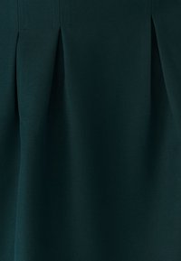 Falda plisada de un verde oscuro hecha de tejido texturizado, que presenta pliegues nítidos y costuras limpias, sin herrajes ni adornos visibles.