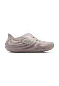 Ένα μονό παπούτσι τύπου slip-on σε χρώμα ταουπ με ραβδωτή σόλα, οπές αερισμού στην κορυφή και ανάγλυφο λογότυπο Nike στο πλάι, εμφανίζεται σε προφίλ από το πλάι.