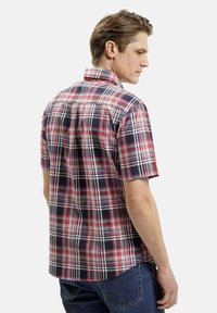 Koszula z krótkim rękawem w kratkę, w czerwone, granatowe i białe wzory, o luźnym kroju i kołnierzyku na guziki.