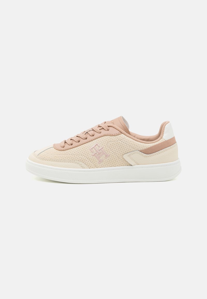 Baskets en beige clair et rose doux, dotées d'une tige perforée, d'accents roses et d'une semelle blanche avec un design bas.