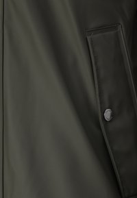 Donkergroene waterdichte jas met een matte afwerking, zijzak met eenklep en een merkdrukknopdetail.