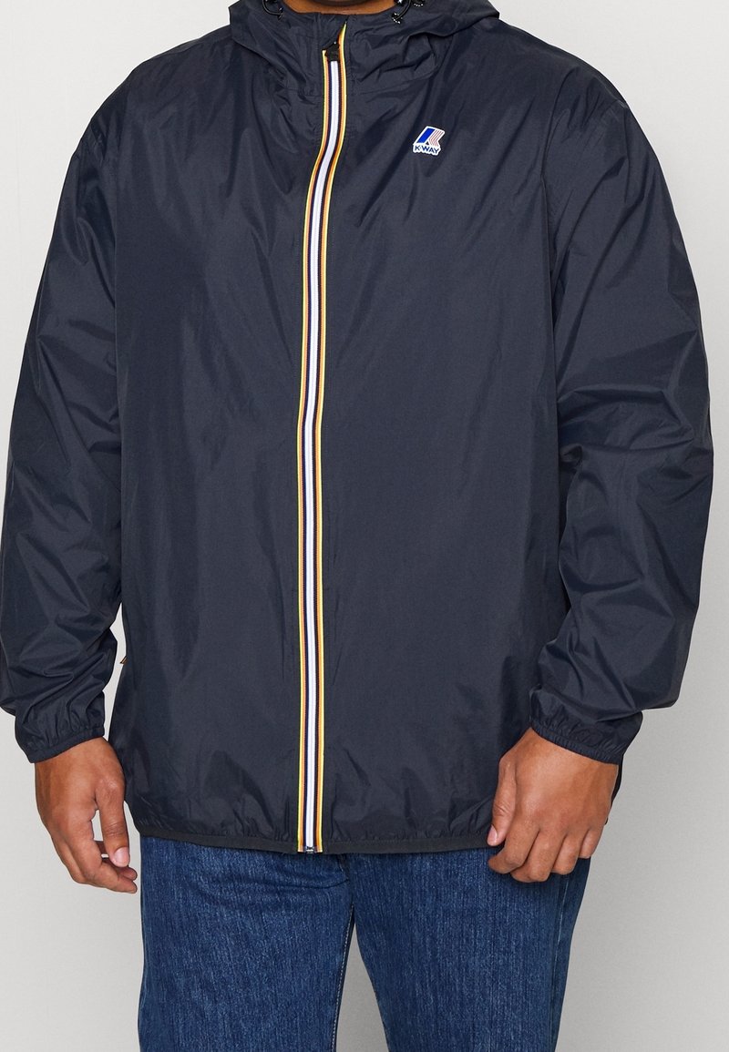 Navy windbreaker jacket with a zip front, featuring yellow, white, and red stripes along the zipper. Elastic cuffs and drawstring hood.