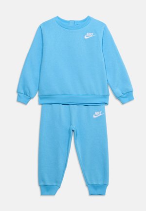 Hellblaues Nike Kinder-Sweatshirt- und Jogginghosen-Set mit weißen Nike-Logos auf Brust und Oberschenkel, Rippbündchen und Rundhalsausschnitt.