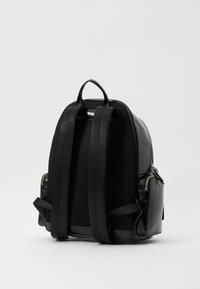 Mochila negra con un acabado de cuero suave, espalda de malla y correas ajustables anchas. Cuenta con un bolsillo con cremallera en el lateral y una asa en la parte superior.
