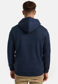 Navy knitted hoodie with a textured finish, featuring a drawstring hood and ribbed cuffs and hem. Simple, casual design.
