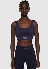 Marineblauw sportcrop top met brede bandjes en een getailleerd ontwerp. Kenmerkt het "HALO"-logo in het wit. Gladde textuur, gecombineerd met bijpassende hoge taille legging.