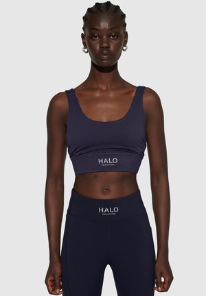 Marineblauw sportcrop top met brede bandjes en een getailleerd ontwerp. Kenmerkt het "HALO"-logo in het wit. Gladde textuur, gecombineerd met bijpassende hoge taille legging.