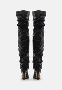 Black leather over-the-knee boots with a slouchy design, pointed heels, and a smooth texture. Features gathered material at the top.