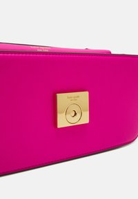 Borsa in pelle rosa con chiusura a lucchetto in tonalità oro, cuciture visibili e dettaglio logo impresso. Tessuto liscio con forma rettangolare.