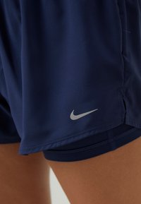 Námořnické sportovní šortky vyrobené z hladké, lehké tkaniny. Mají všitou vnitřní šortku a stříbrné logo Nike na spodní straně.