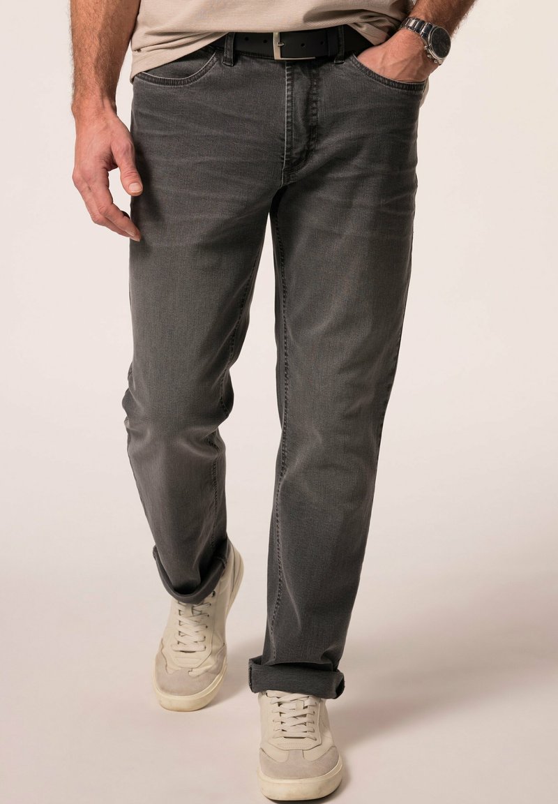 Szare dżinsy o luźnym kroju, z talią na średnim poziomie, z podwiniętymi mankietami i kieszeniami z przodu. W zestawieniu z jasnymi sneakersami.