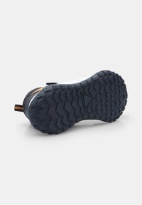 Suola in gomma con un motivo di battistrada robusto, di colore blu navy scuro. Riconoscibile da una linguetta arancione e una parte superiore bianca.