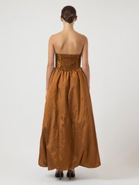 Strapless brown satin gown with a smocked bodice and a flowing, full-length skirt. Smooth texture with a glossy finish.