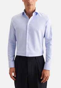 Camicia a maniche lunghe blu chiaro con apertura a bottoni e colletto strutturato. Realizzata in tessuto morbido con dettagli di texture discreti.
