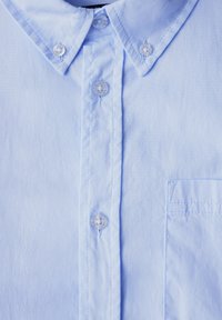 Light blue button-up shirt featuring a classic collar, clear buttons, and a single chest pocket with subtle stitching details.