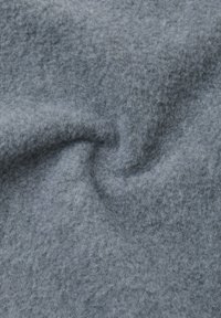 Tessuto morbido e testurizzato di un grigio chiaro con un motivo sottile, caratterizzato da un design delicatamente vorticoso che mette in risalto la sua consistenza pelosa.
