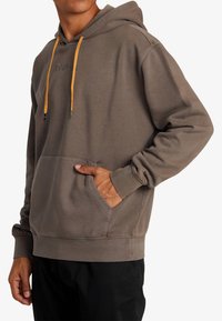 Grijze hoodie met een trekkoord, voorzien van gele accenten, een voorkant zak en geribde boorden, gemaakt van zacht materiaal en met een relaxte pasvorm.