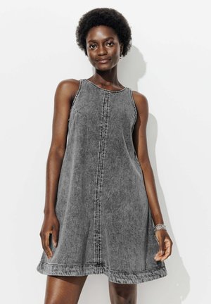 Robe sans manches en denim noir avec une coupe décontractée, dotée d'un col rond, d'un détail de couture central et d'un ourlet évasé.