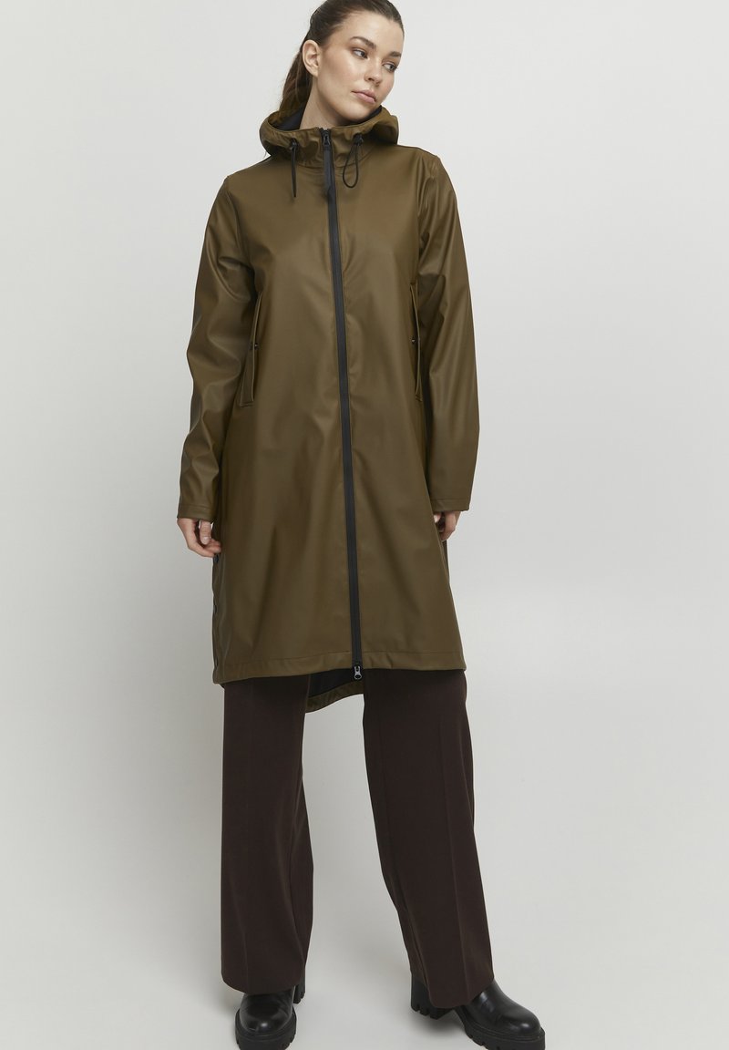Trăsătoriță waterproof de culoare verde măsliniu, cu glugă, având un fermoar frontal și două buzunare laterale. Textură netedă, design până la genunchi, șnururi ajustabile.