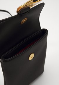 Borsa nera in pelle con texture liscia, accessori in oro e chiusura a scatto. L'interno è foderato in rosso e presenta un comparto.