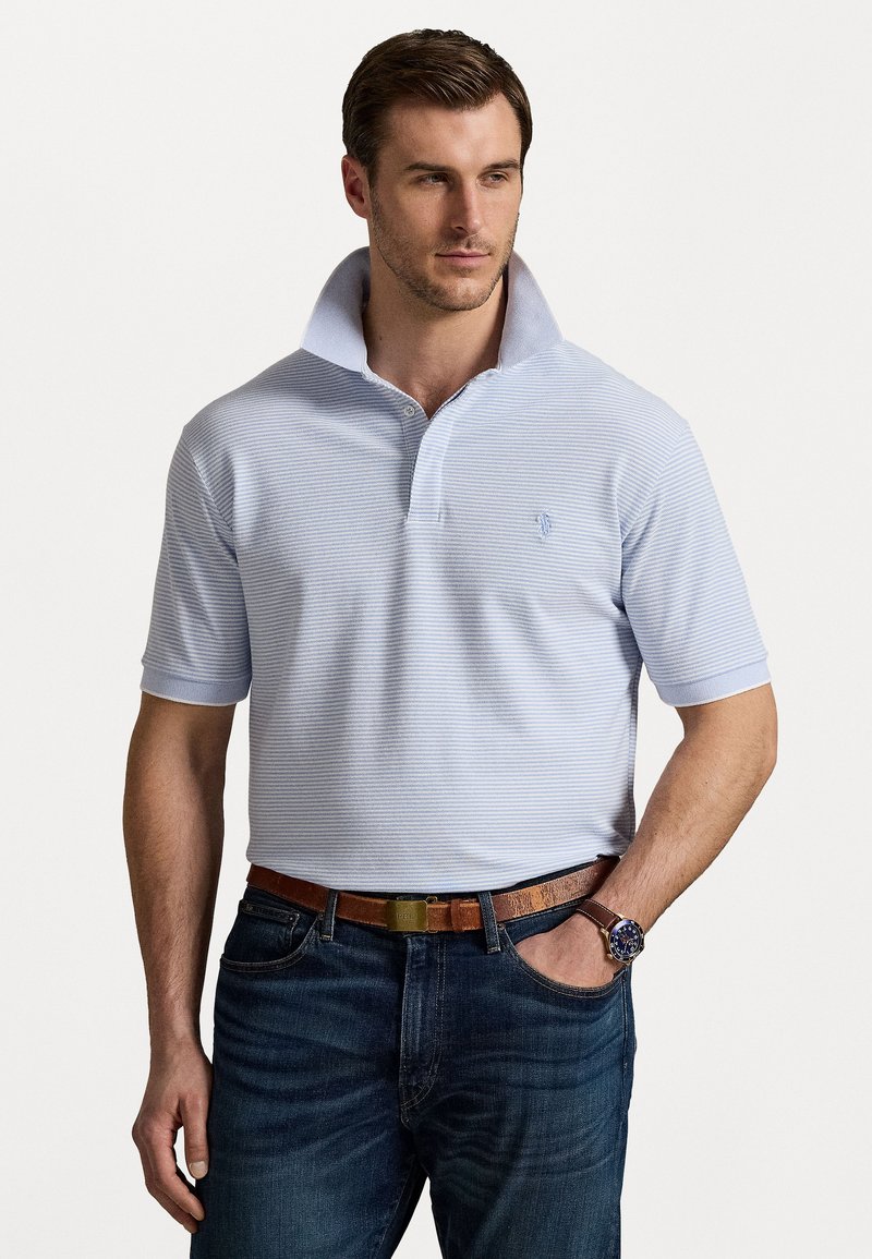 Lyseblå stripete polo skjorte med brett krage, korte ermer og et lite emblem på brystet, kombinert med mørke jeans og et brunt belte.