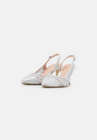 Silver slingback-klackar med spetsig tå, prydda med glittrande rhinestones och släta textilaccenter, med låg klack och justerbart band.